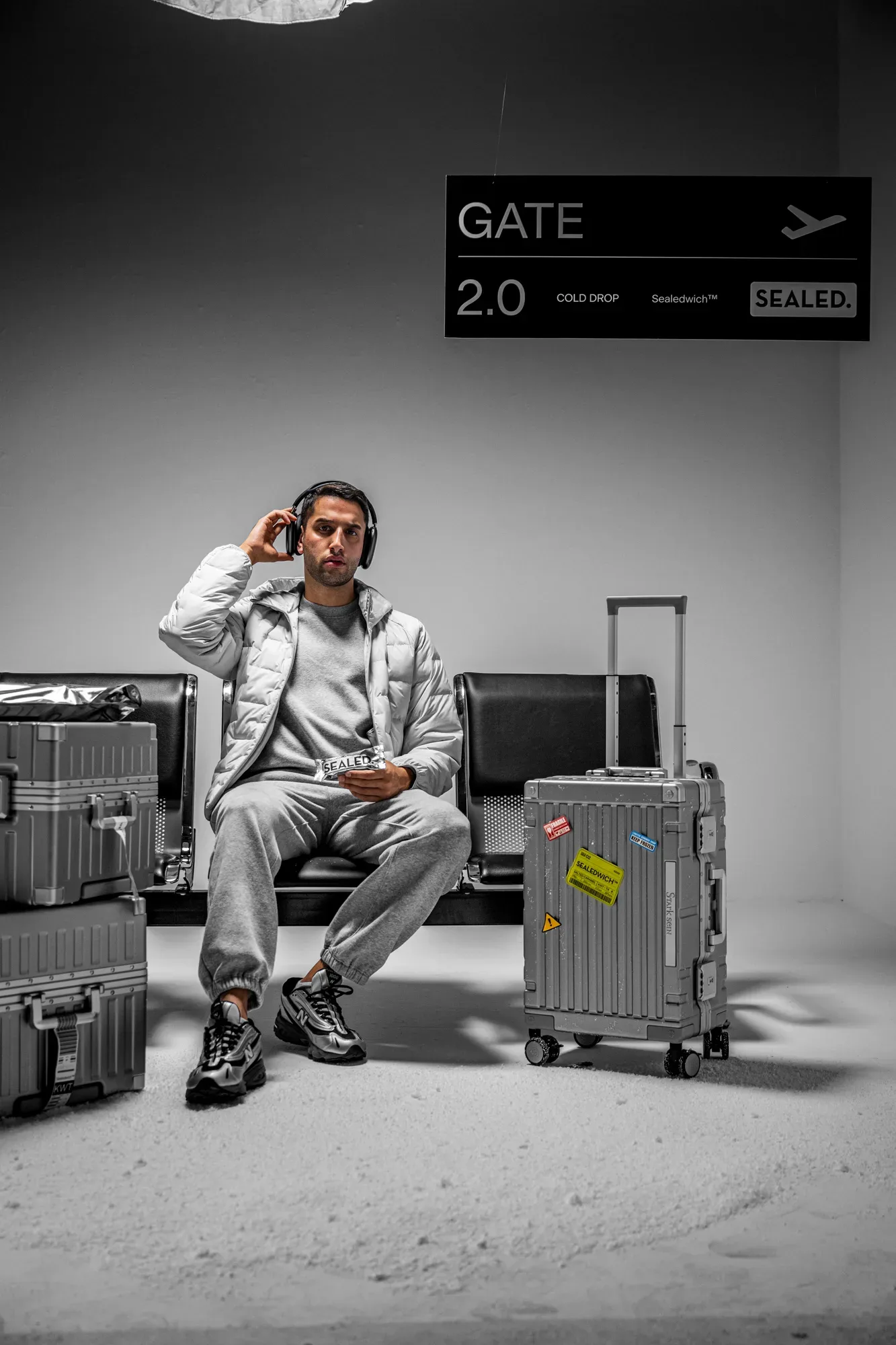 SEALED summer campaign, a traveller waiting at a departure gate with silver suitcases