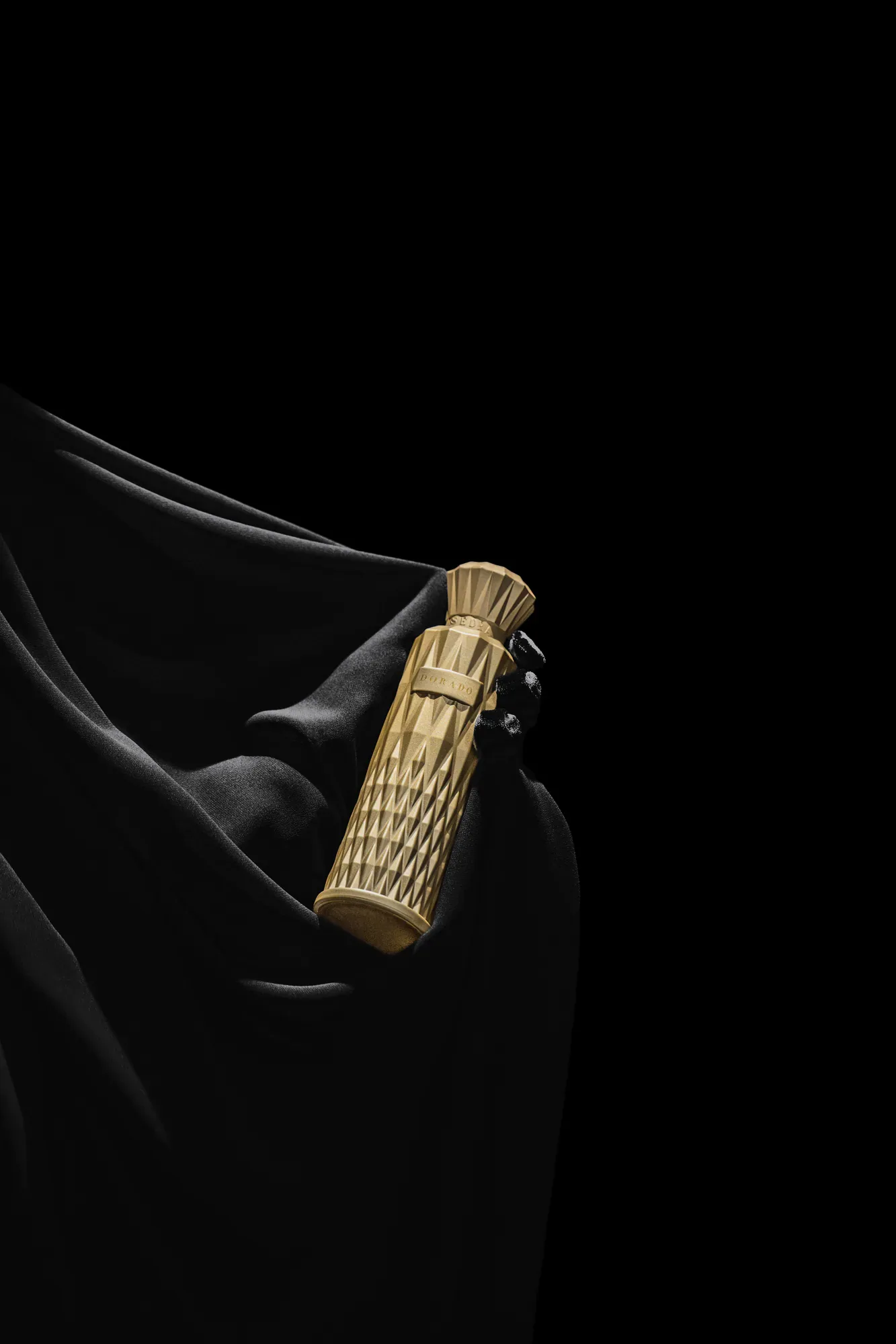 Gold Sedra perfume bottle against sculpted black fabric